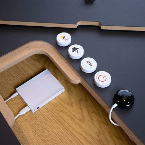 Smart home control buttons on a wooden surface with a black device connected.